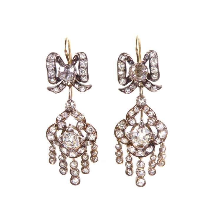Pair of diamond quatrefoil cluster pendant earrings, with fringe below and from ribbon bow tops